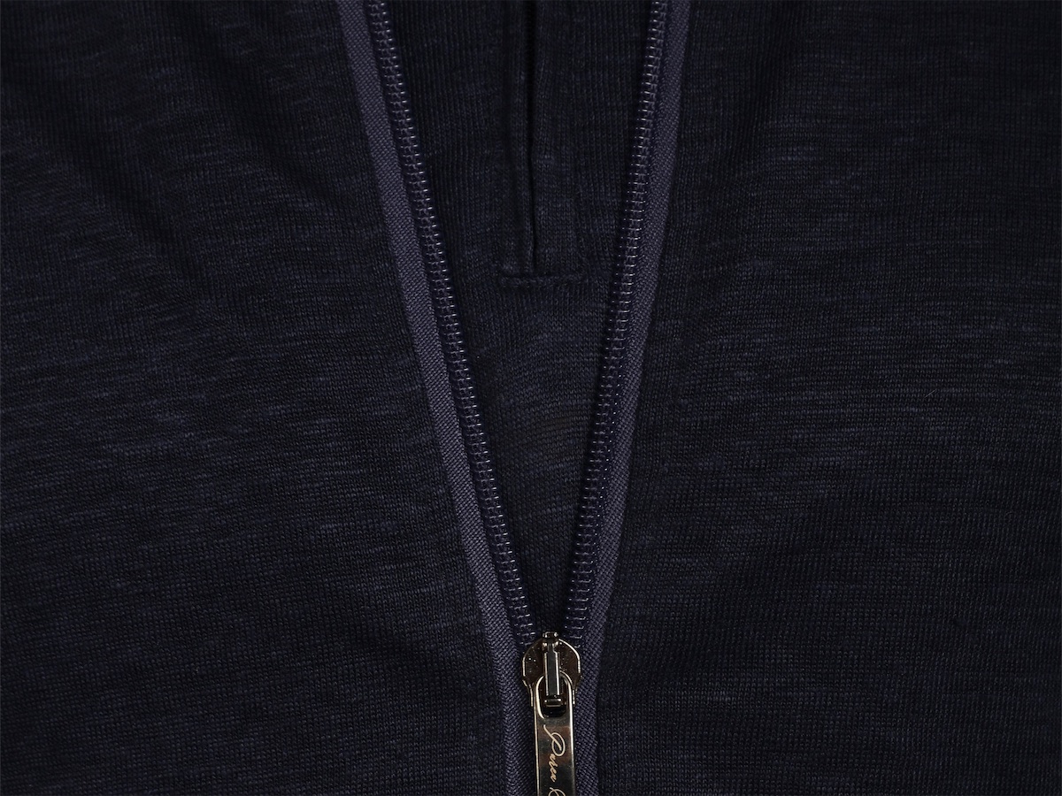 The full-length zip of a navy blue sailor jacket, with its engraved pull.