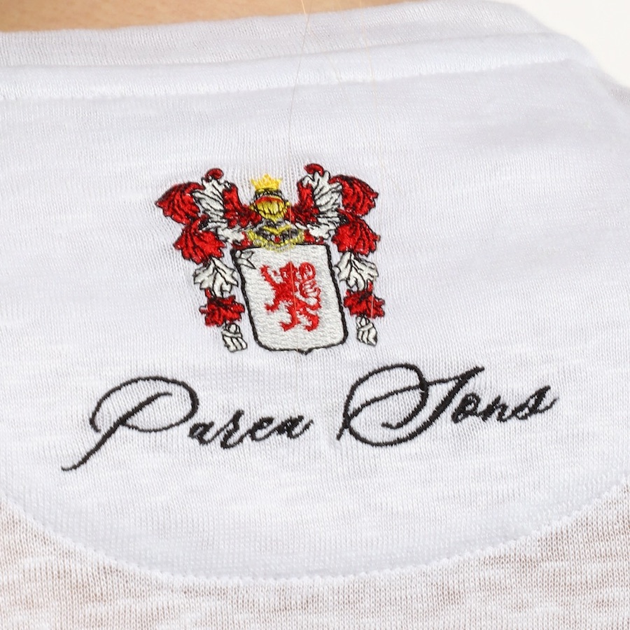 The Parea Sons crest embroidered on the linen cloth, up close.
