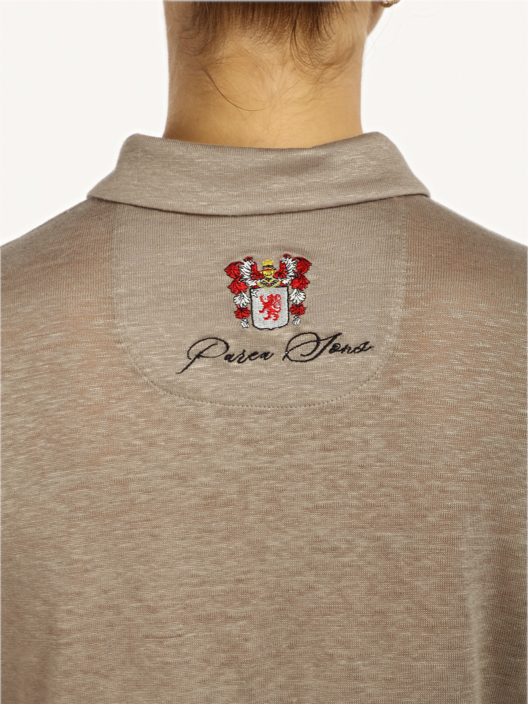 The crest embroidered on the taupe polo, stitch by stitch.